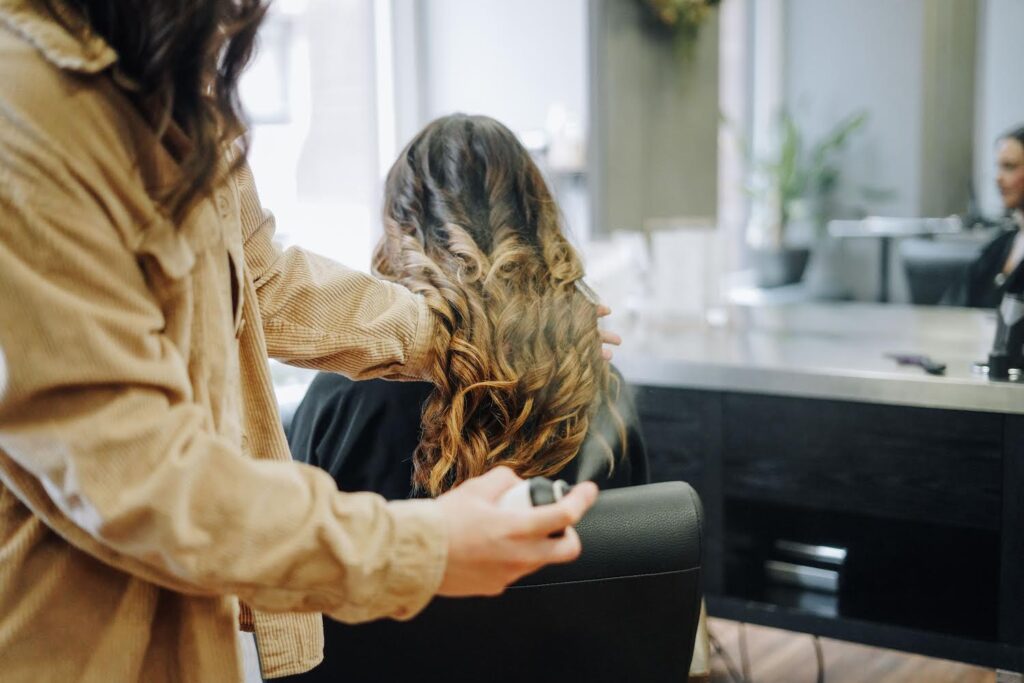 Picture of one of the stylists at Hustle and Heart salon in Duluth, MN using product on an extension client.